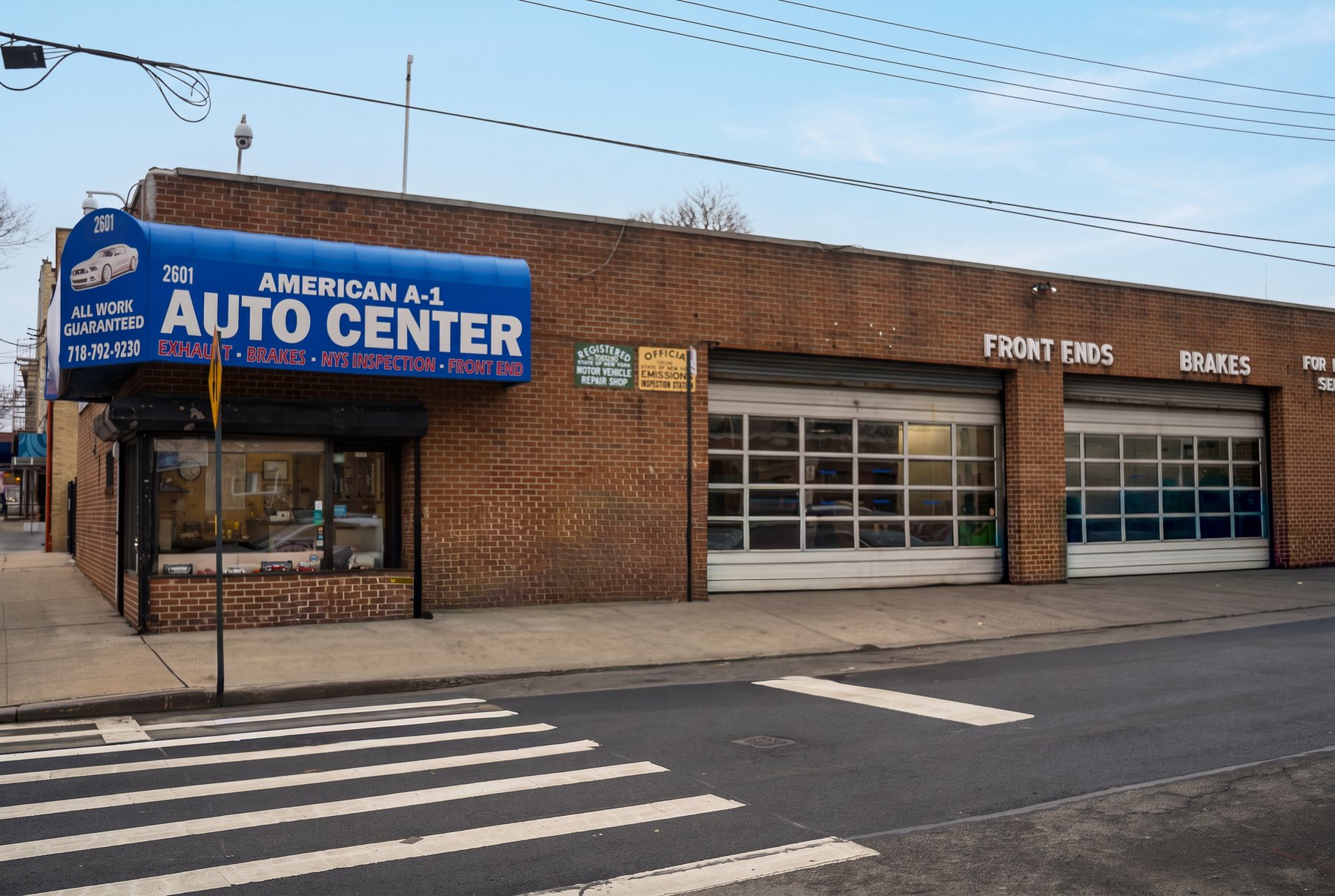 American A-1 Auto Center's brick building and blue awning at 2601 Saint Raymond Avenue in the Bronx